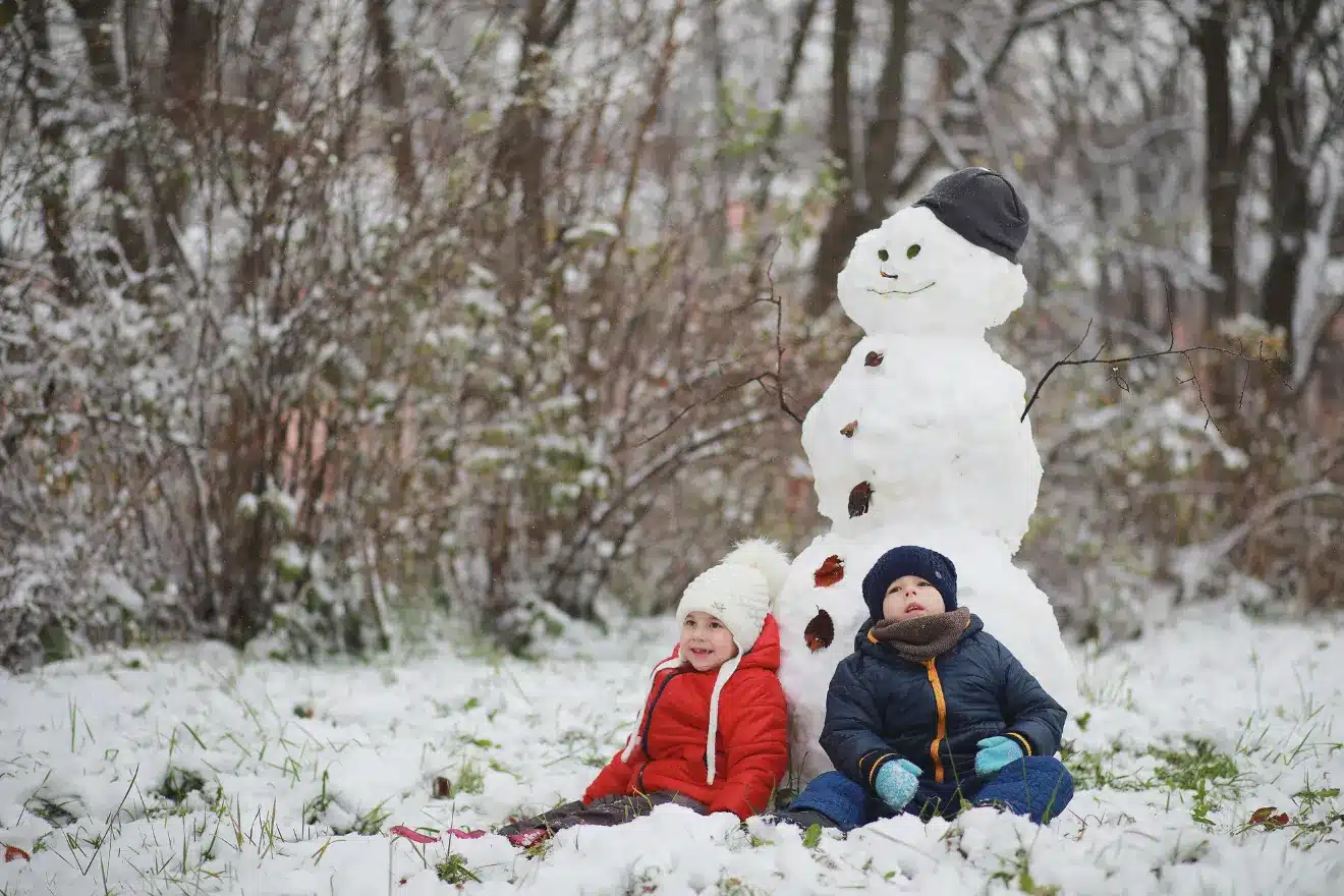 boy and girl lying against a snowman