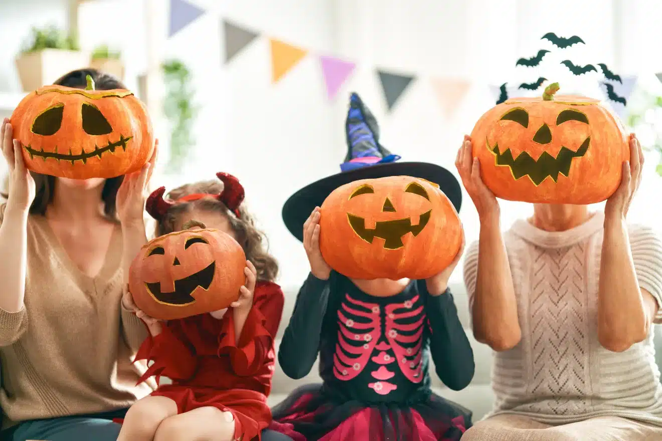 kids and women holding carved pumpkins around their heads