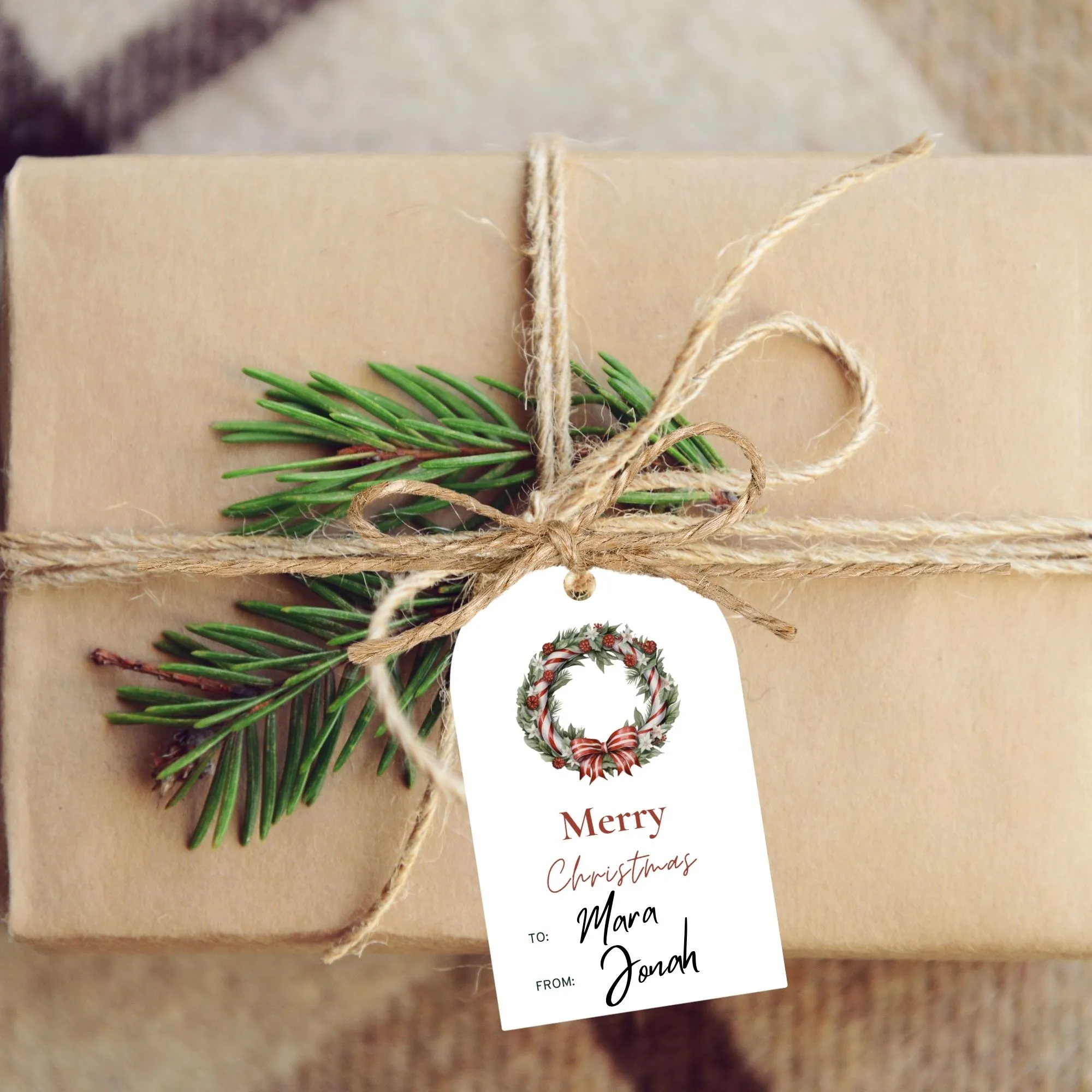 A brown paper-wrapped gift with twine and evergreen sprigs, featuring a tag that reads "Merry Christmas To: Mara From: Jonah.