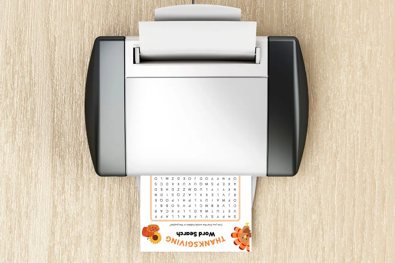 A printer on a wooden surface prints a Thanksgiving-themed word search puzzle.