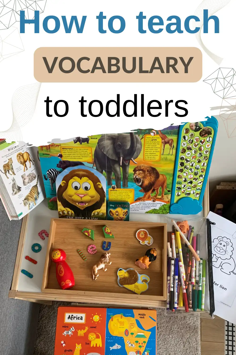 A table with animal books, coloring pages, markers, animal figurines, and puzzles arranged for teaching vocabulary to toddlers.