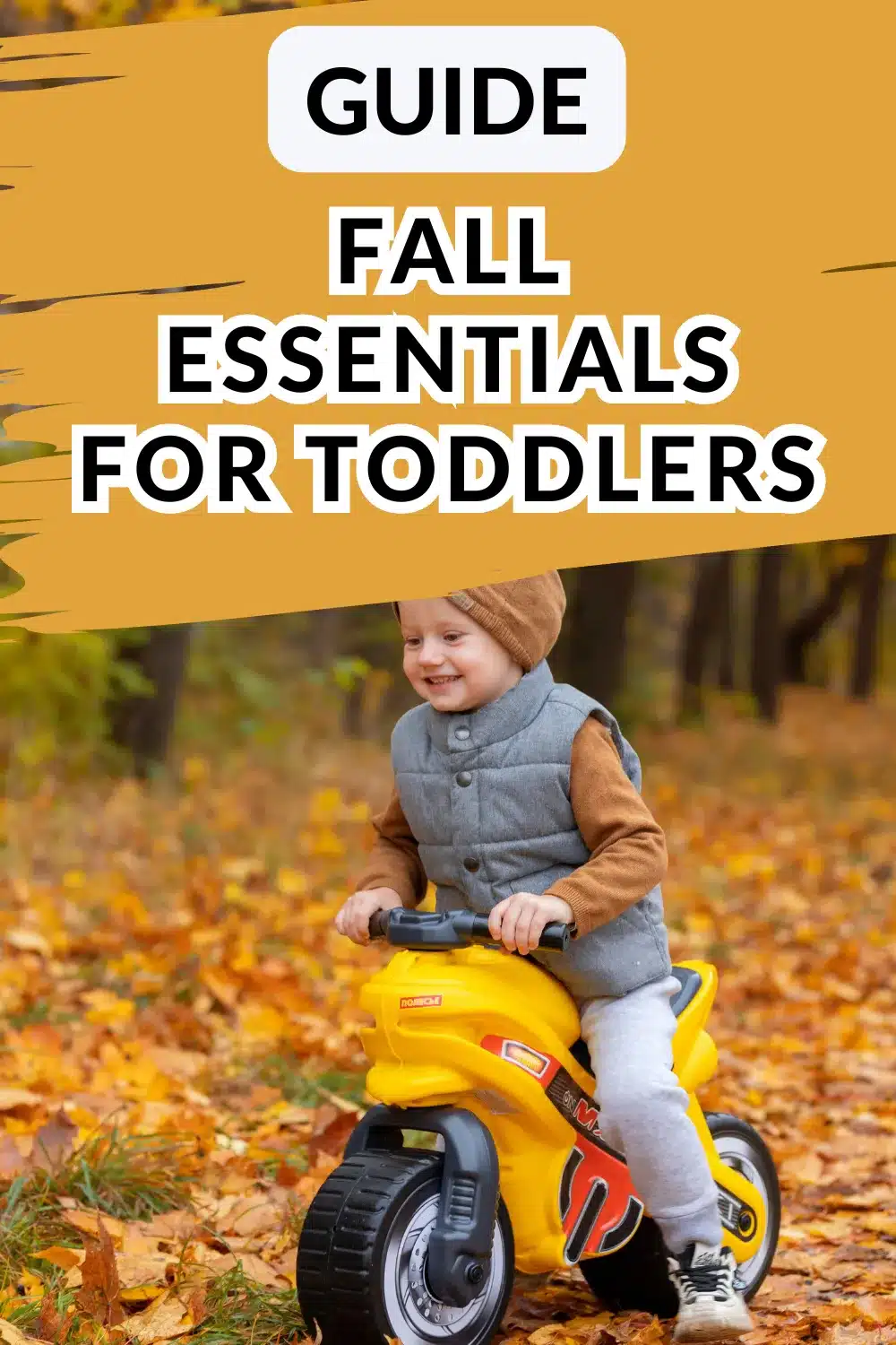 A young child in fall clothing rides a yellow toy motorcycle outdoors on a path covered with autumn leaves. Text overlay reads "Guide Fall Essentials for Toddlers.